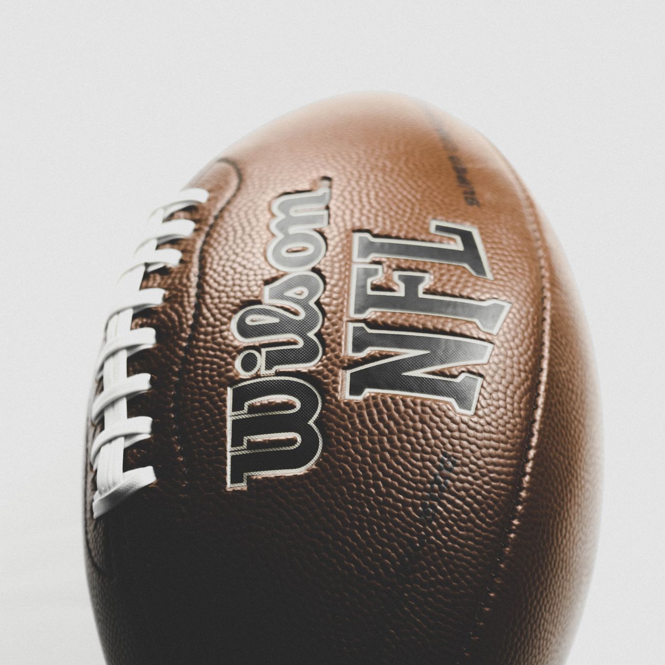 Close up of a Wilson NFL leather football captured in a studio setting, highlighting texture and branding.