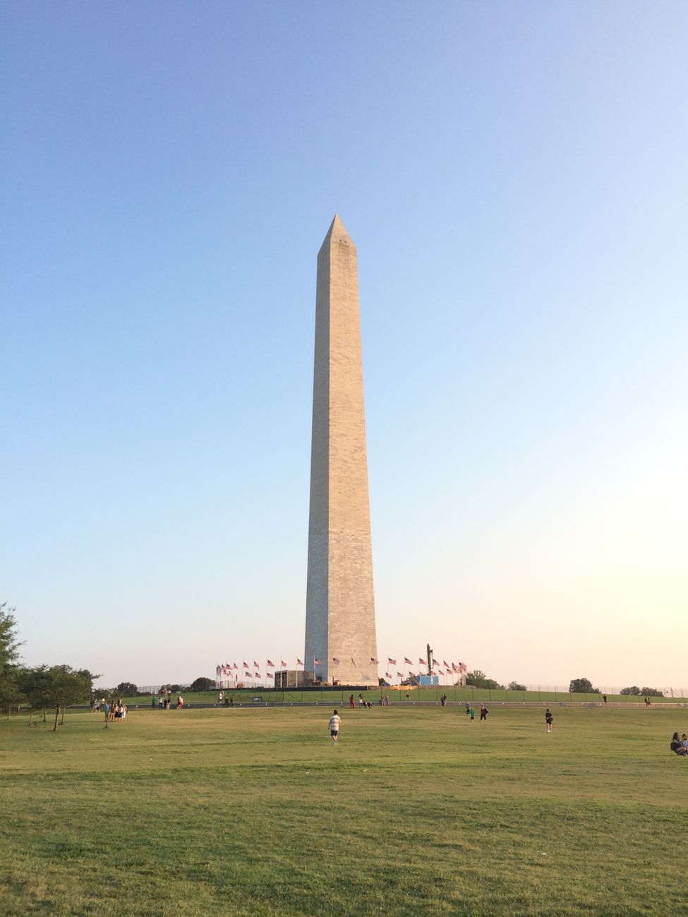 A view of the Washington Monument surrounded by green lawns and a clear blue sky, ideal for travel enthusiasts.
