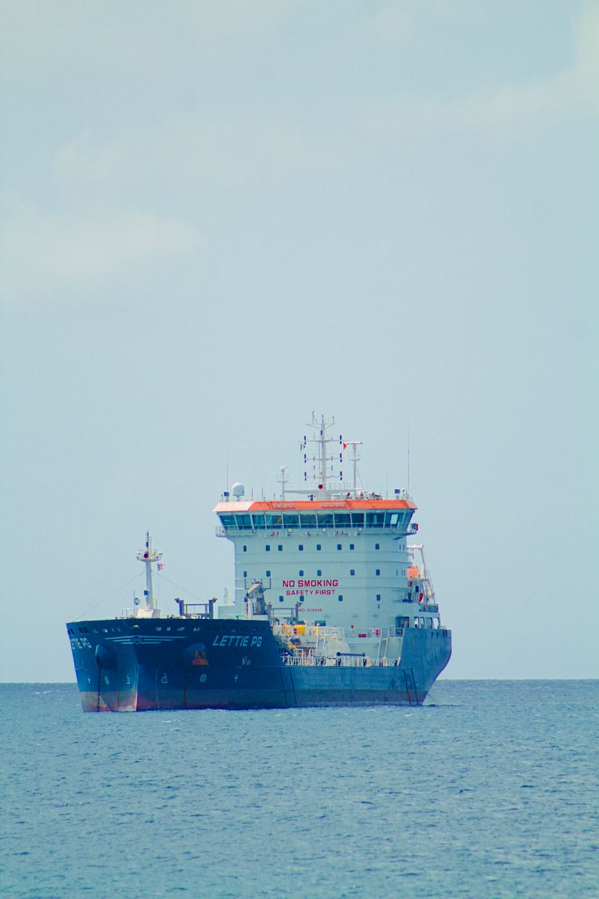 A large cargo ship navigates calm ocean waters under a clear sky. Perfect for maritime themes.