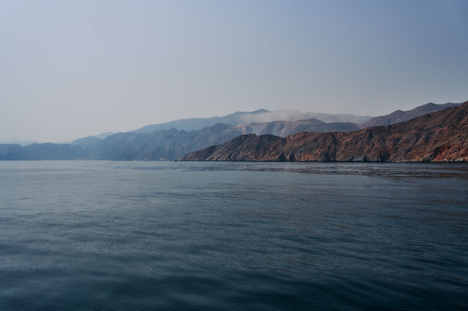 A serene view of the mountains and sea in Musandam, Oman during daylight.