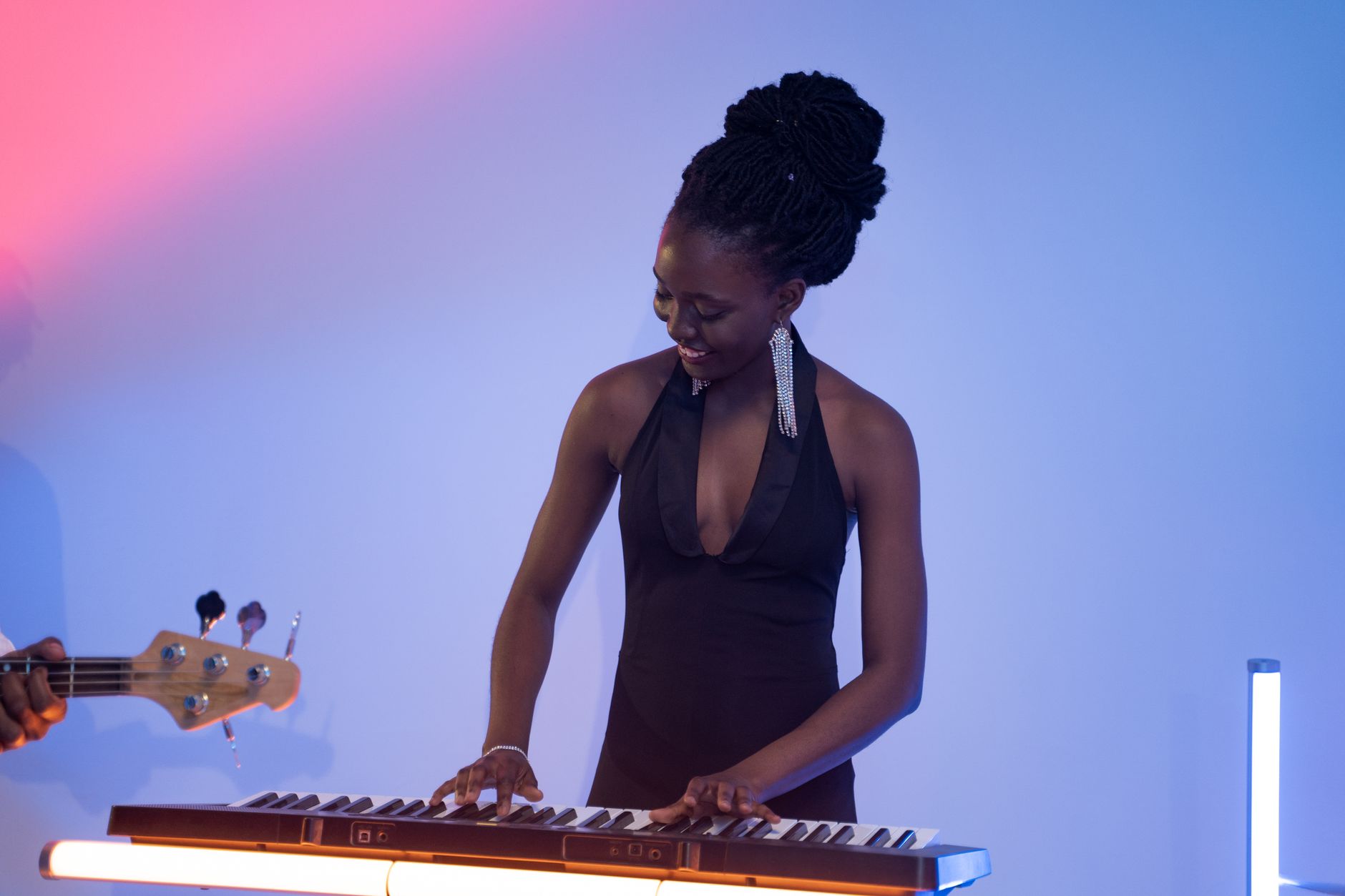 Elegant woman playing a keyboard in a colorful studio setting, showcasing musical talent and enjoyment.
