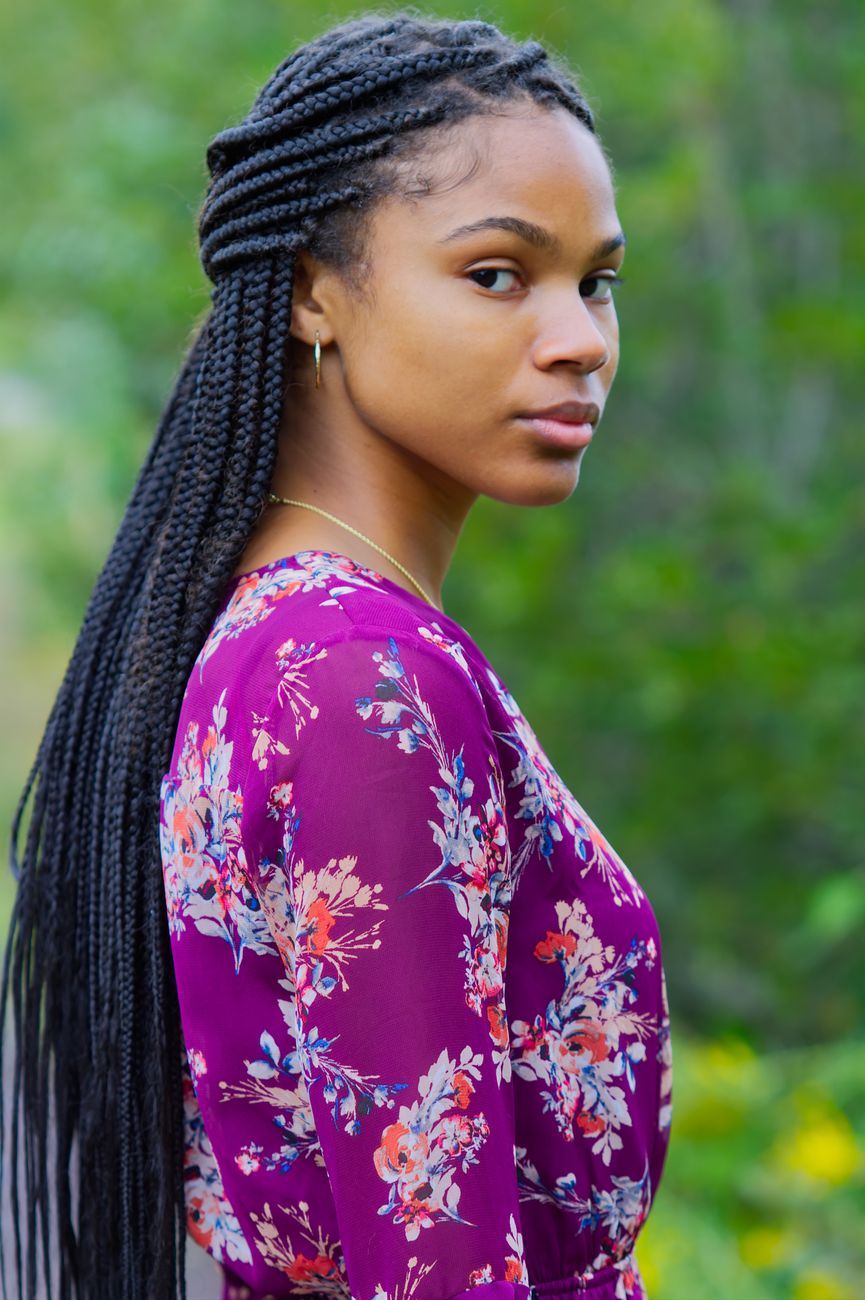 Fashionable African American woman with braided hair in floral dress, outdoors.