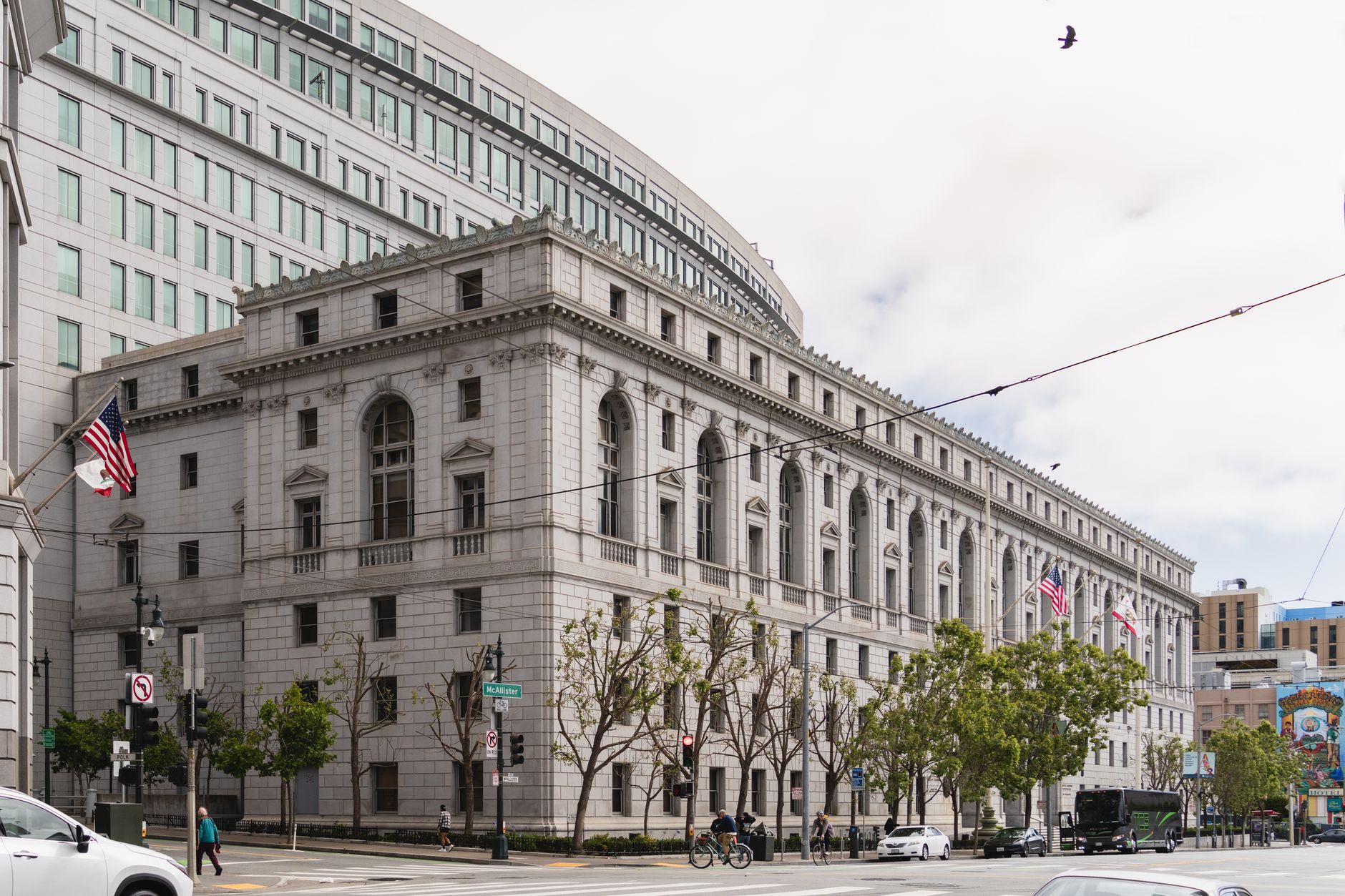 Elegant neoclassical courthouse in San Francisco with American flags outside.