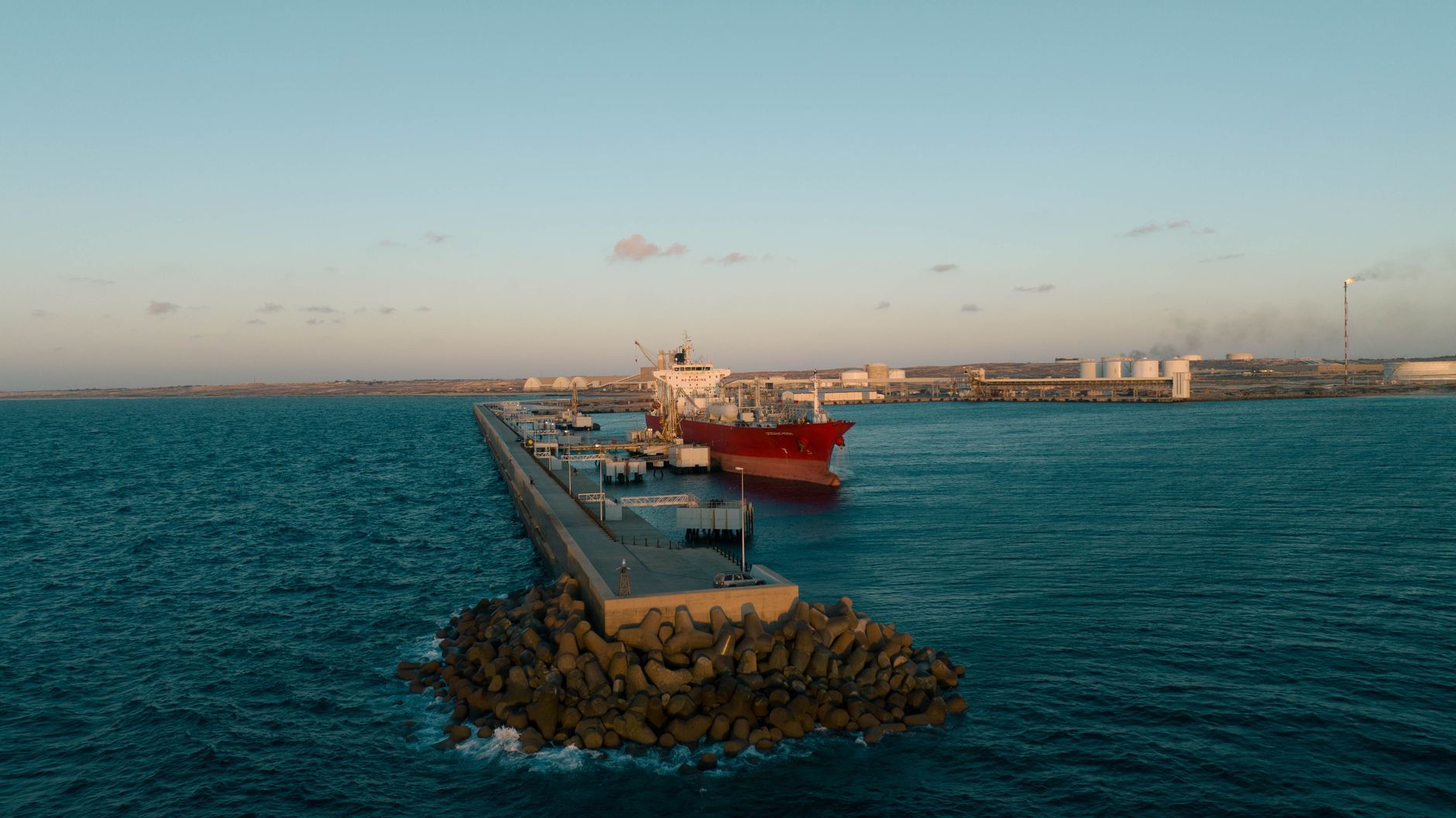 Aerial view of a large cargo ship at an industrial harbor in Libya during daytime.