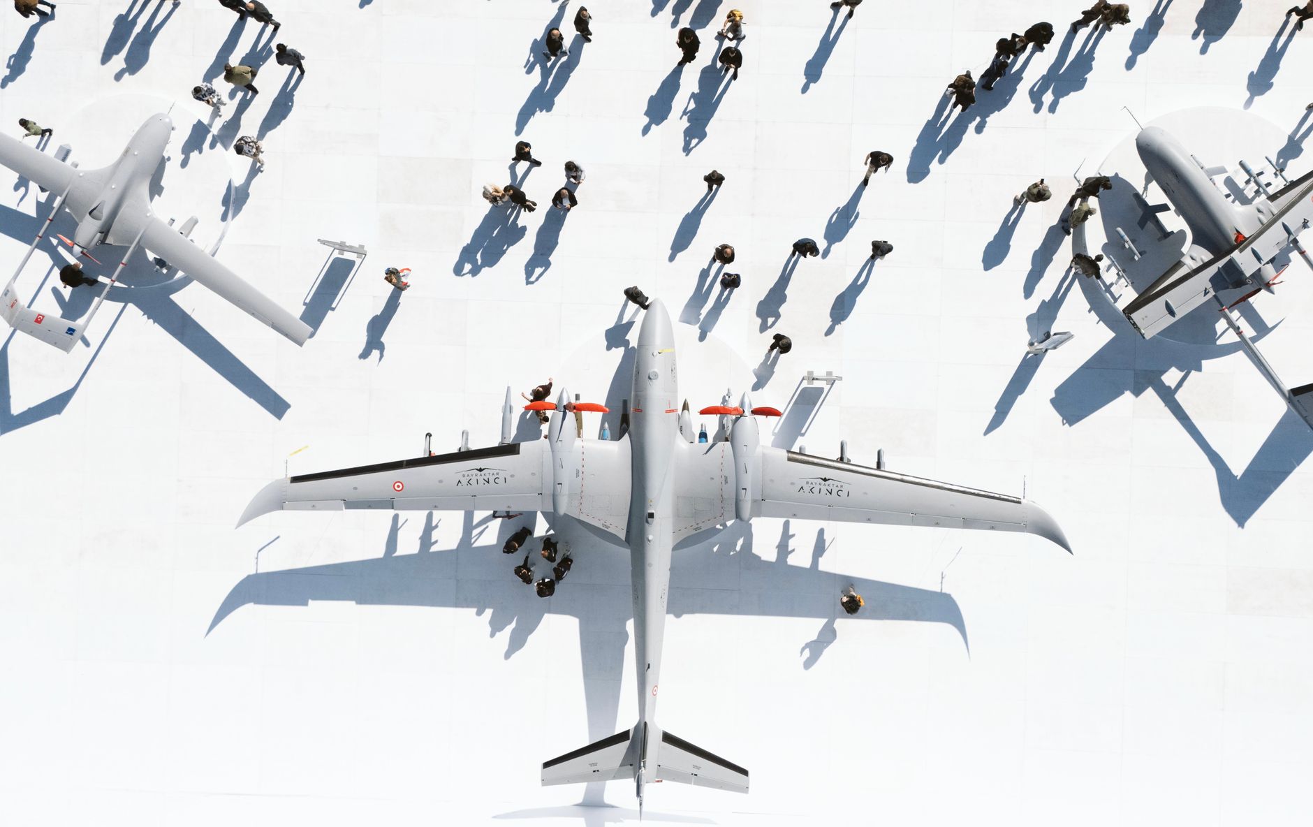 Aerial view of military jets with people and shadows on a sunny day.