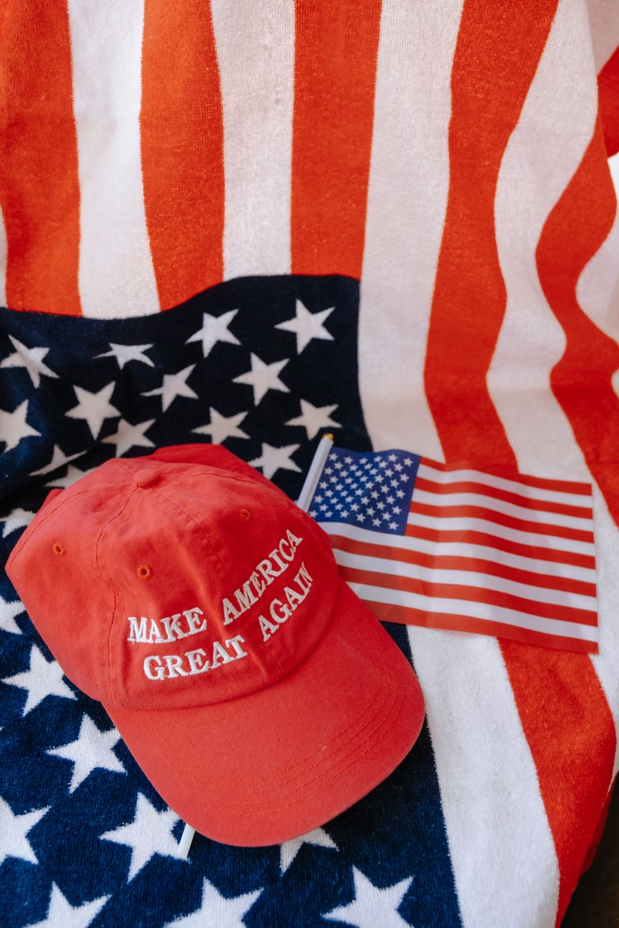 Red cap with 'Make America Great Again' text on US flag background.
