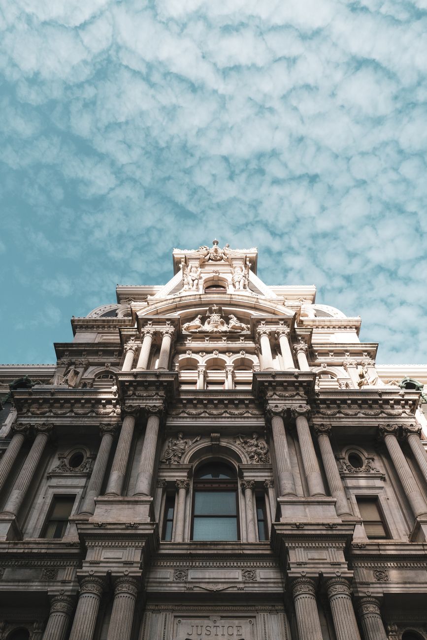 Low angle view of historic Philadelphia City Hall under a cloudy sky, showcasing classic architectural details.