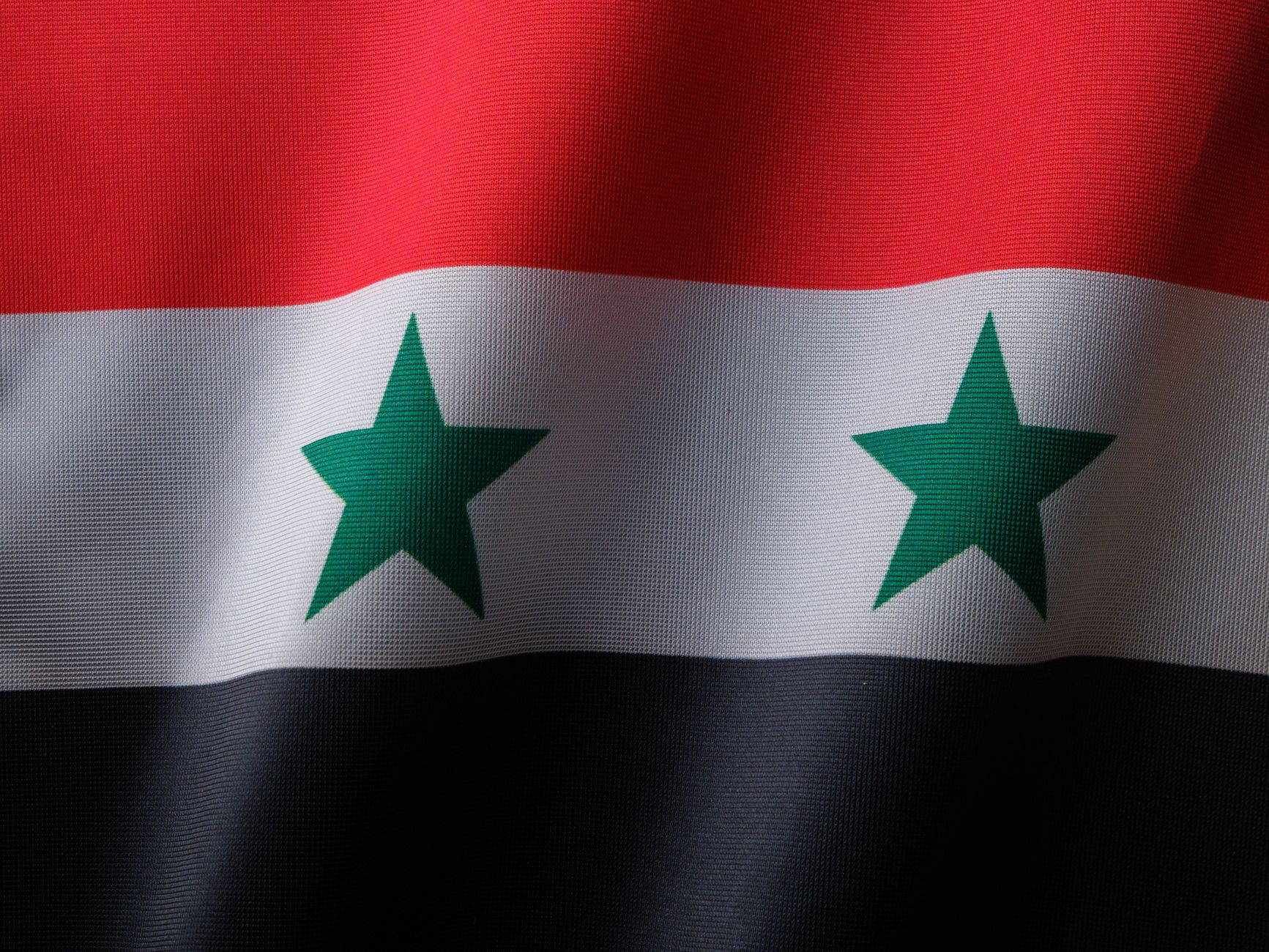 High quality close up of the Syrian national flag with textile texture.