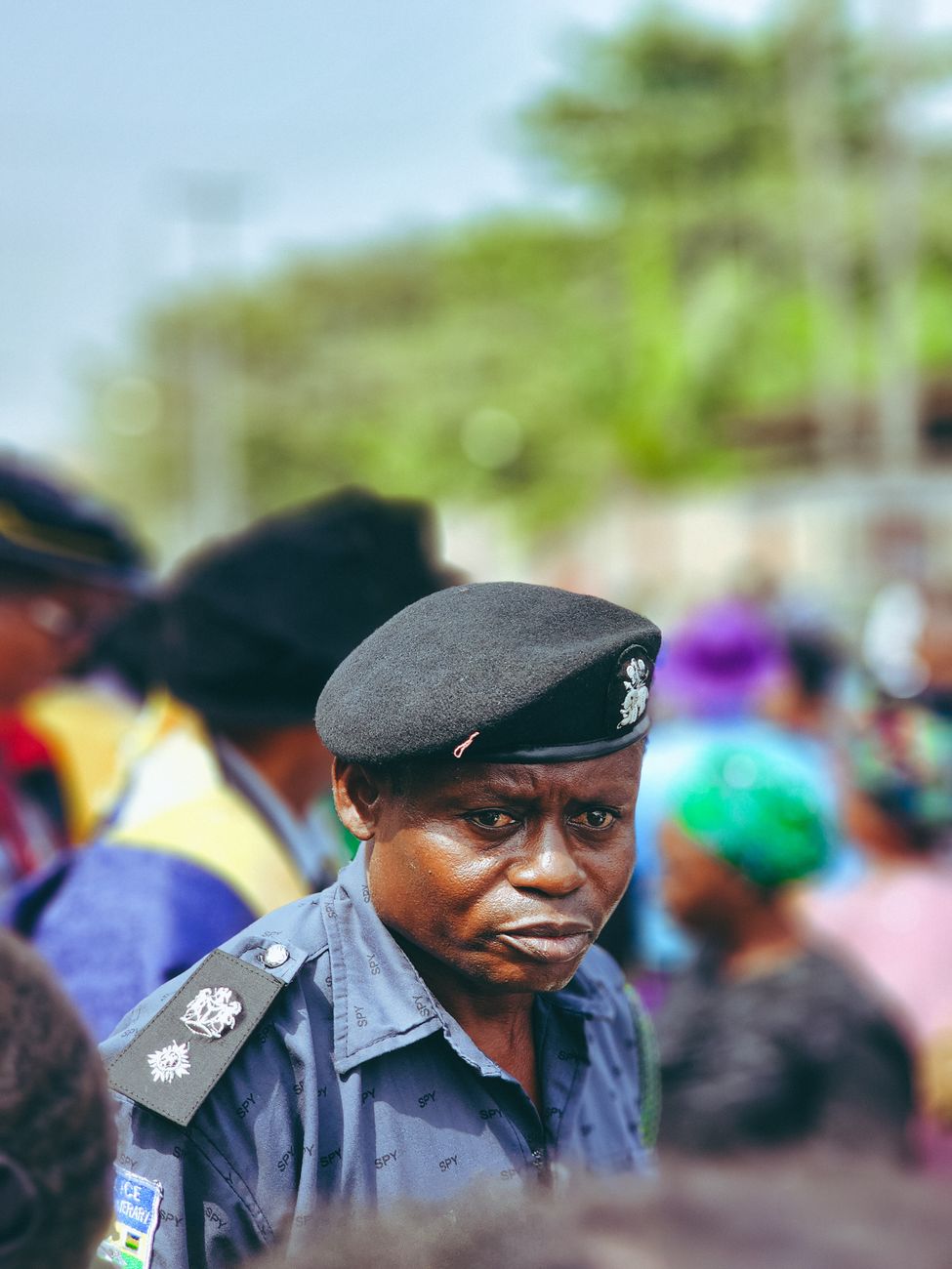 A police officer in uniform amidst a crowd at an outdoor event, conveying security presence.
