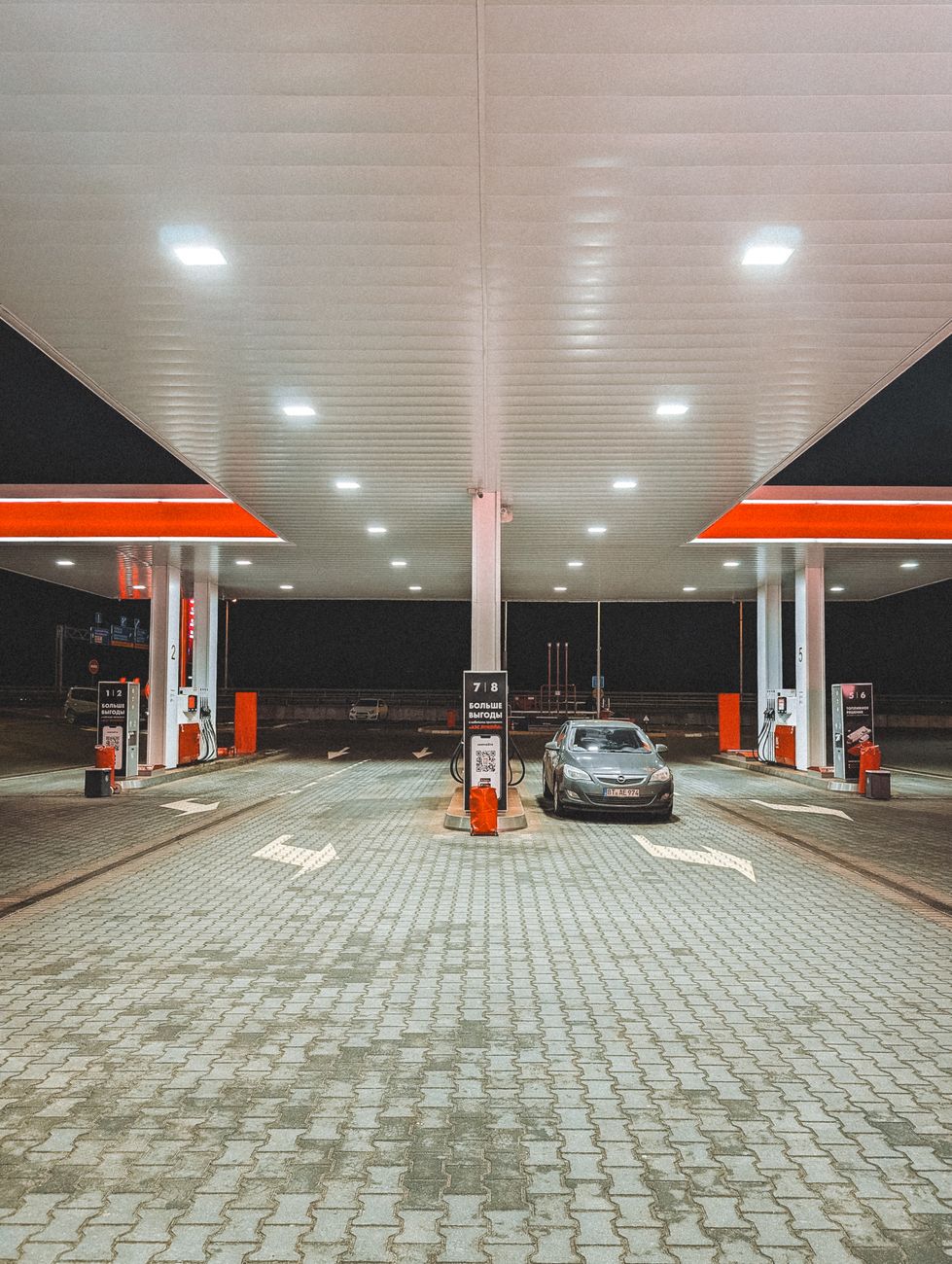 A vehicle parked at a brightly lit modern gas station during nighttime.