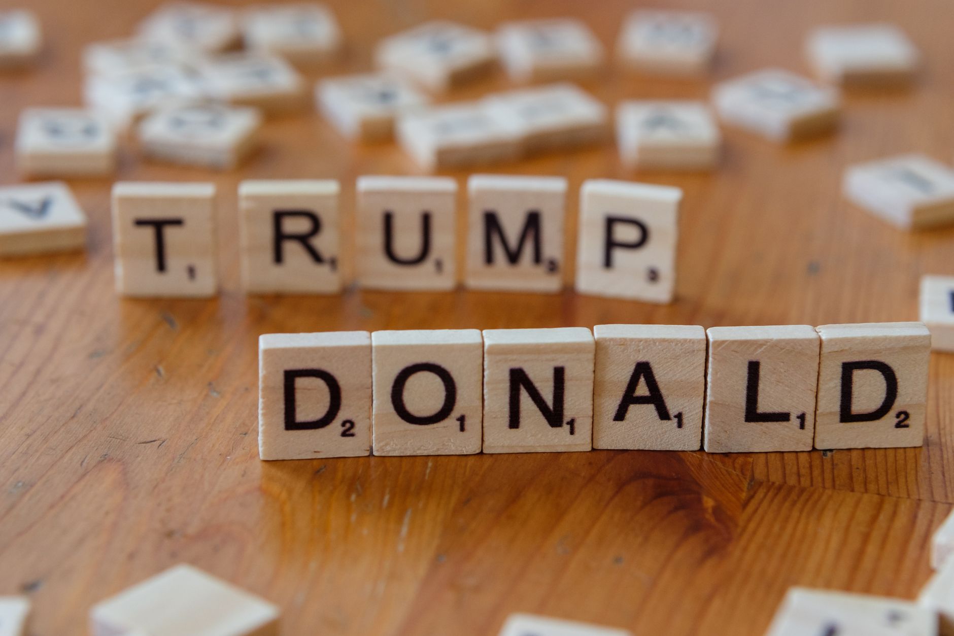 Close up of Scrabble tiles spelling 'Donald Trump' on a wooden table.