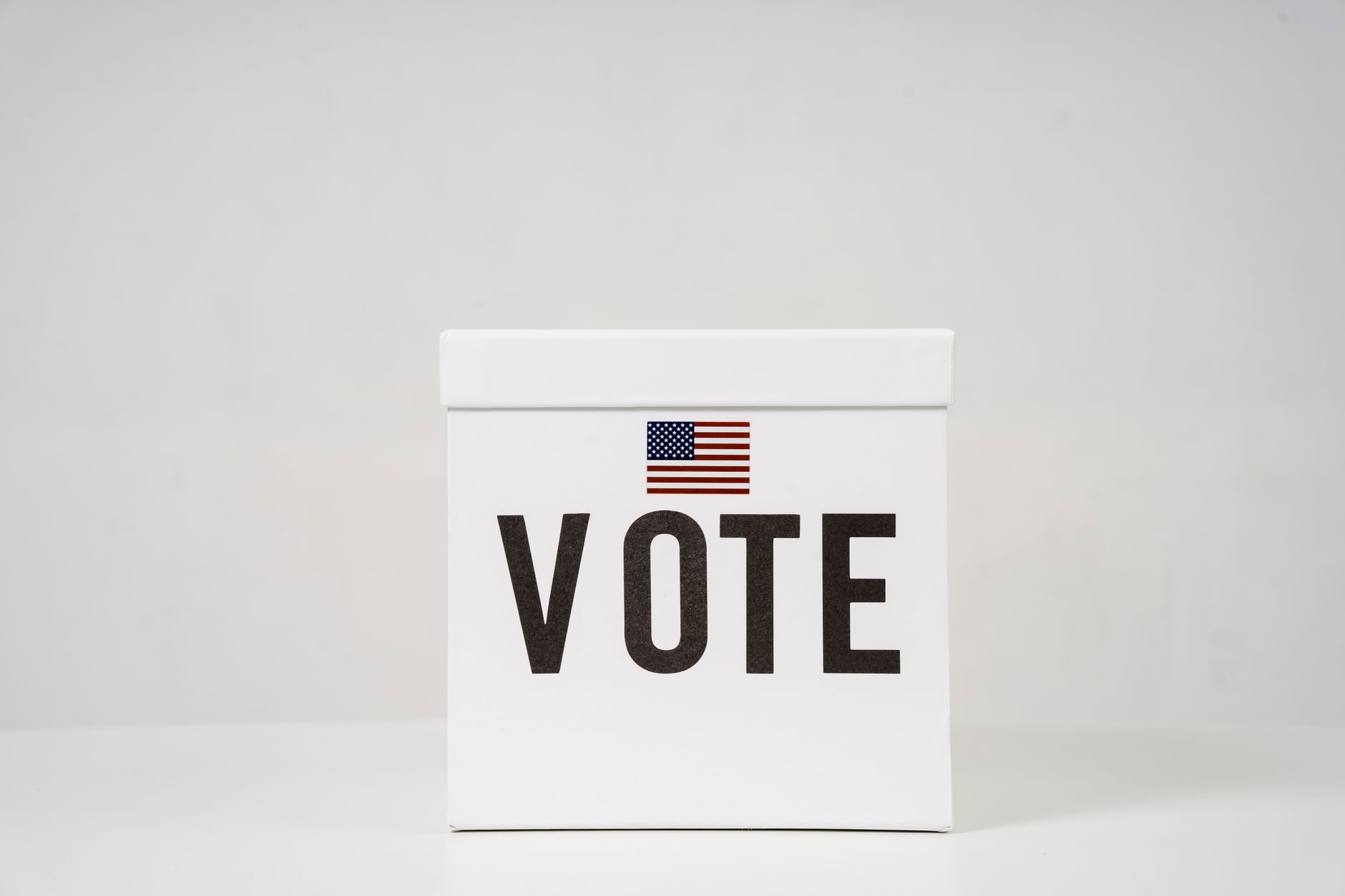A minimalist ballot box with 'Vote' and an American flag, symbolizing elections.
