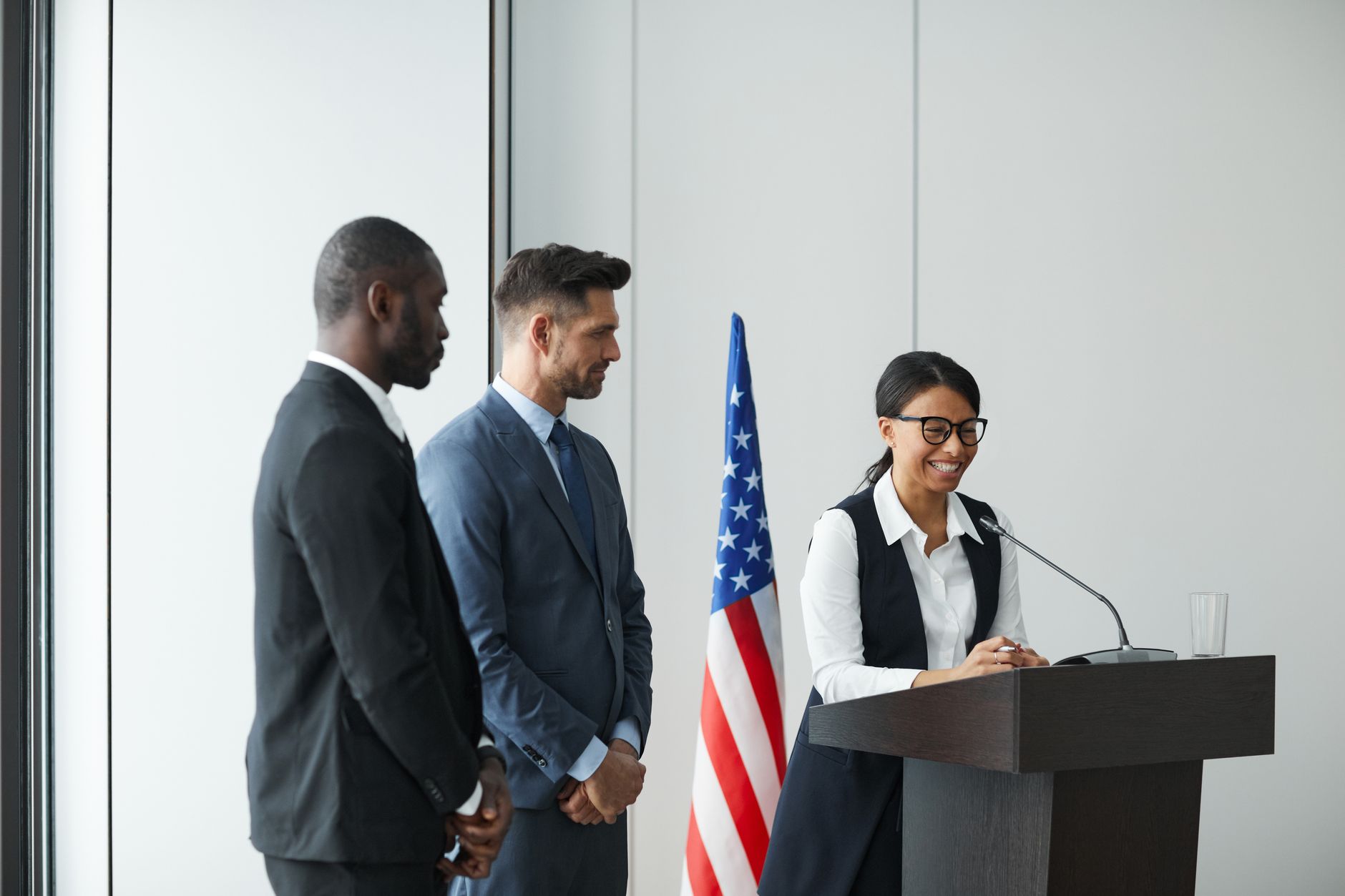 A diverse team in business attire at a podium with an American flag, showing unity and professionalism.
