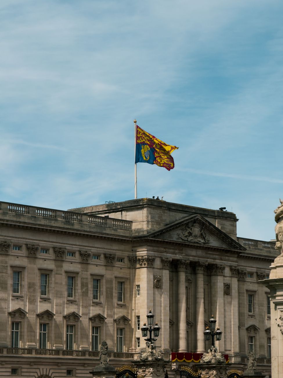 Iconic view of Buckingham Palace with the Royal Standard Flag flying high, set against a clear sky.