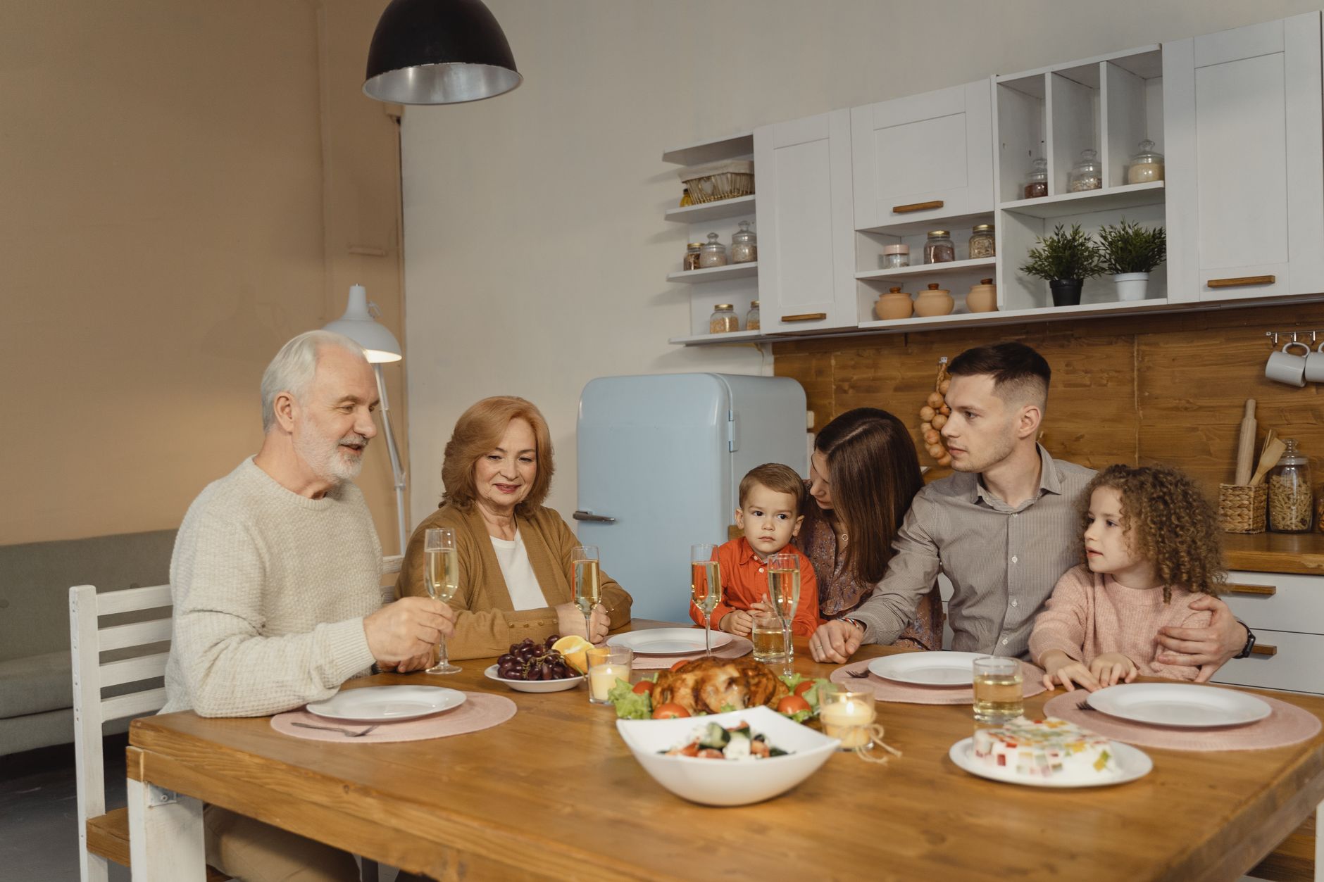 A multi generational family enjoying a dinner together in a warm, cozy kitchen setting.