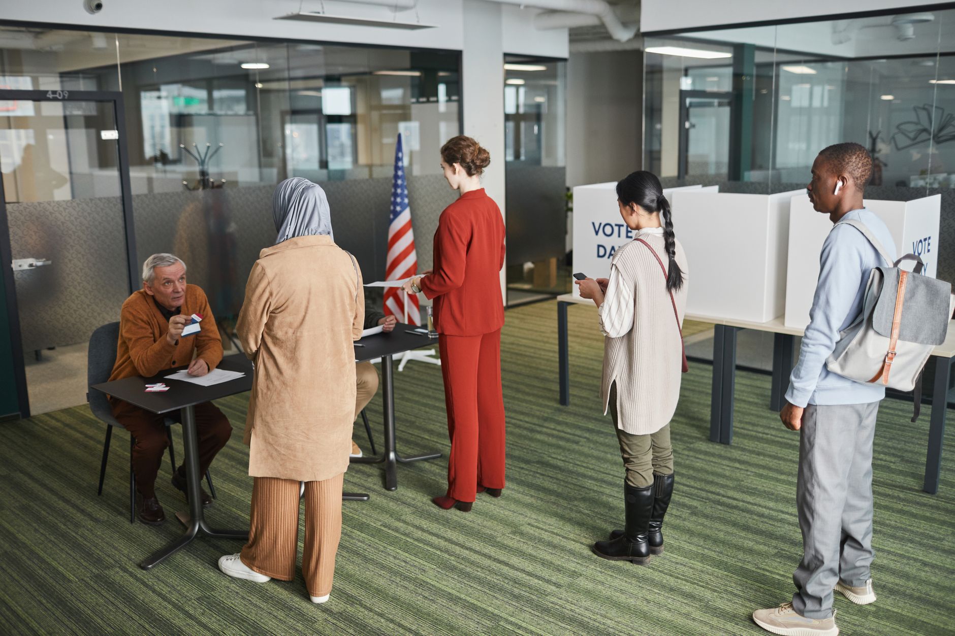 Diverse group of voters lining up at an indoor polling station on election day.