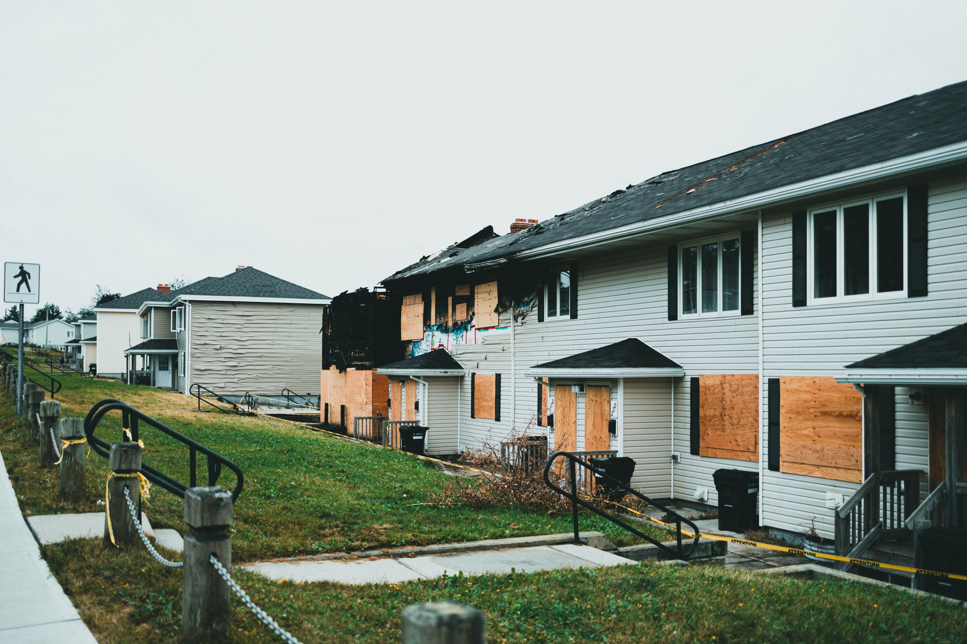 Boarded up suburban homes with visible fire damage and neglect.