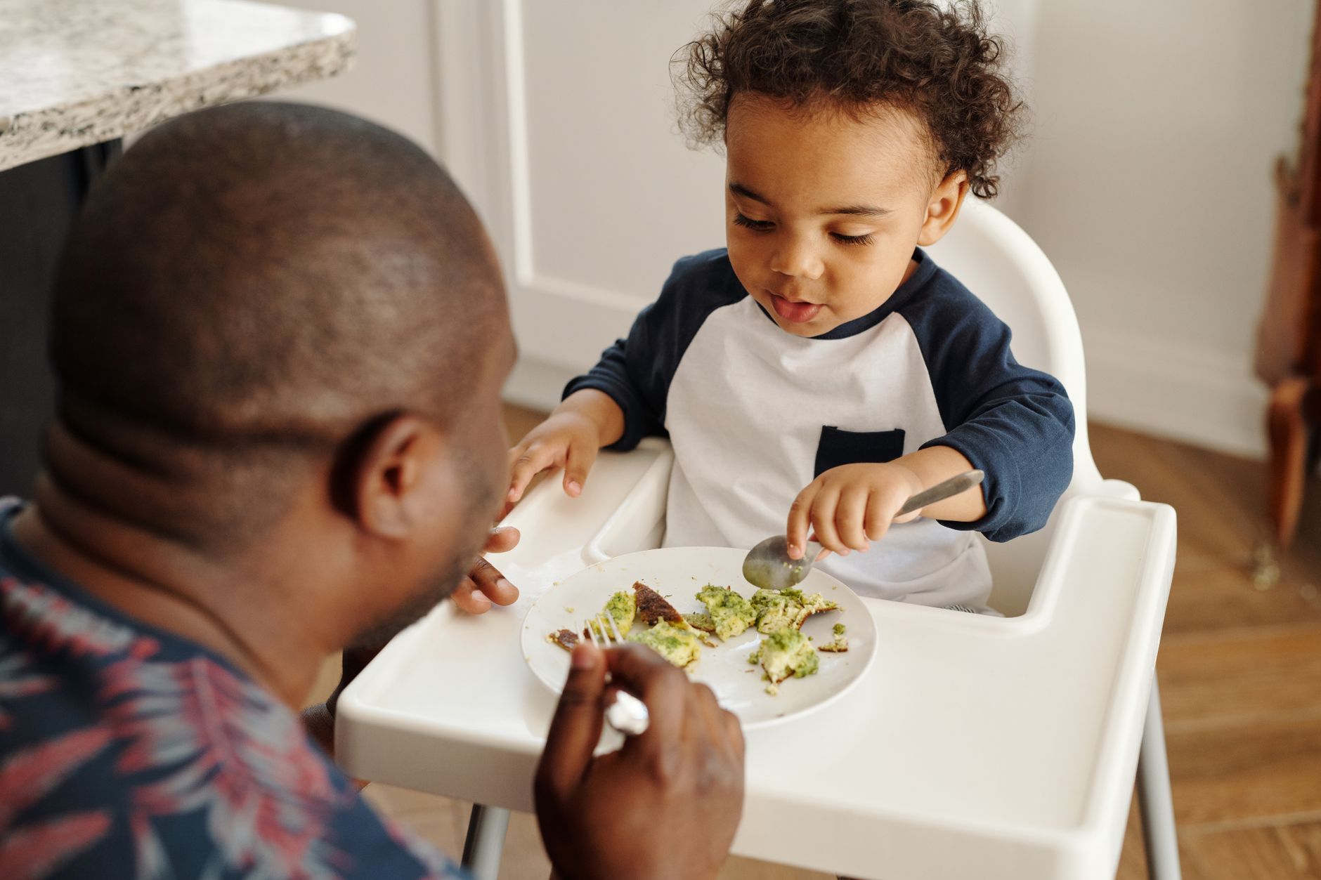 Father and young son bonding over a meal at home in the kitchen.