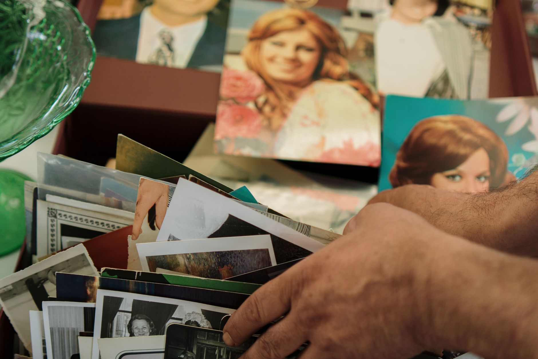 Close up of hands sorting through a collection of vintage family photos.